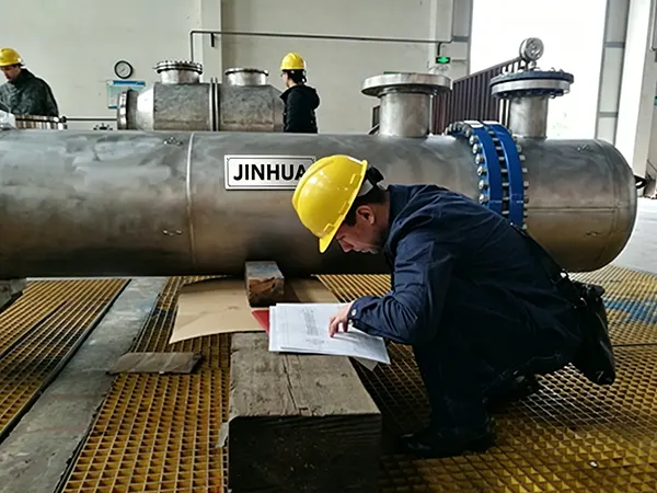 Technician conducting Factory Acceptance Test and reviewing specs for a stainless steel shell and tube heat exchanger
